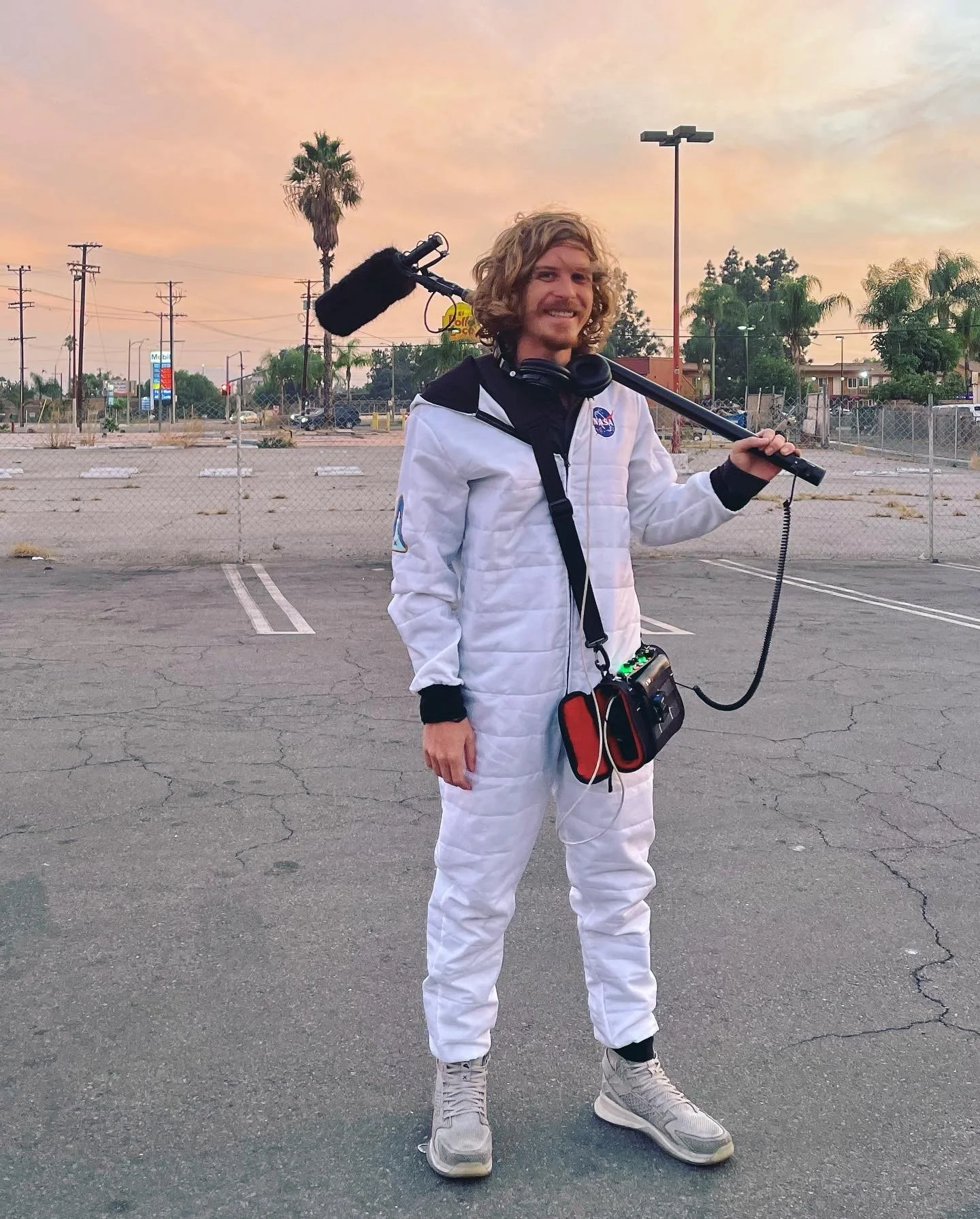 Mason Hankins on location in Los Angeles holding a boom microphone and production sound bag